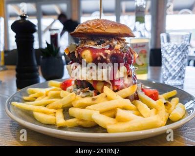 Hamburg, Deutschland. April 2024. Ein Teller mit einem Hamburger und Pommes Frites steht auf dem Tisch in einem Restaurant. Quelle: Markus Scholz/dpa/Alamy Live News Stockfoto