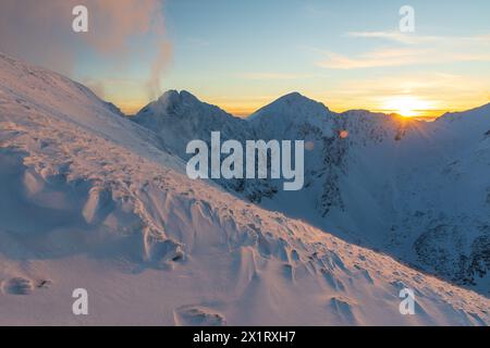 Farbenfroher Winteruntergang in der Westtatra. Blick von Volovec auf die Rohace. Farbenfroher Himmel und beleuchtet durch die Sonne Schnee im Vordergrund. Stockfoto