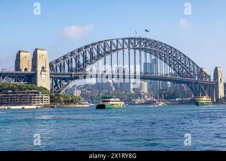 Die berühmte Sydney Harbour Bridge mit Passagierfähren, die über die Bucht hin und her fahren. Eine Bogenbrücke verbindet den Central Business Distr Stockfoto