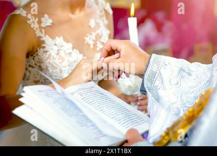 Eheringe austauschen. Priester, der goldene Eheringe an den Fingern anzieht, Braut und Bräutigam in der Kirche in der Hochzeit Ehe. Traditionelle religiöse Hochzeit Stockfoto