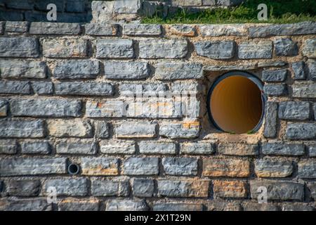 Industrie trifft auf Antike in der Gegenüberstellung einer großen Pfeife gegen feste Steinmauern, die Moderne mit Geschichte verbinden. Stockfoto