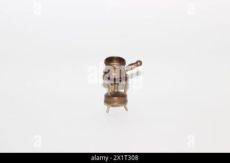 Ein Miniatur-Vintage-Fondue-Topf aus Kupfer auf einem Mini-Brenner Stockfoto