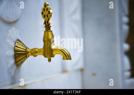 Ein luxuriöser goldener Brunnenhahn mit komplizierten weißen Marmormustern, der Eleganz und Opulenz ausstrahlt. Stockfoto