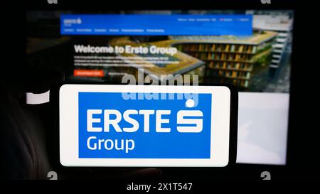 Person mit Mobiltelefon mit Logo des österreichischen Finanzdienstleistungsunternehmens erste Group Bank AG vor der Webseite. Schwerpunkt auf dem Display des Telefons. Stockfoto