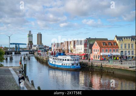 Husum Hafenviertel Stadtbild im Herbst, farbenfrohe Gebäudefassaden, blaues Schiff mit Fluss vor der Tür, horizontale Aufnahme Stockfoto