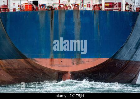 Große blaue Containerschiffe mit Ruder schieben eine riesige Welle durch den Ozean. Stockfoto