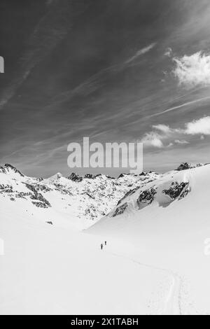 Athleten, die an einem sonnigen Tag im Hinterland Ski fahren, mit einer Landschaft aus verschneiten Bergen. Schwarz-weiß. Stockfoto