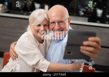 Lächelndes Seniorenpaar, das zu Hause Selfie macht. Porträt eines Seniorenpaares Stockfoto