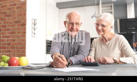 Seniorenpaar, die ihre Rechnungen zu Hause überprüfen. Senior Pärchen, die Rechnungen berechnen Stockfoto