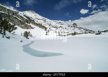 Pacific Crest Trail. Eine schneebedeckte Bergkette mit einem kleinen Fluss, der durch sie fließt. Der Himmel ist klar und blau Stockfoto