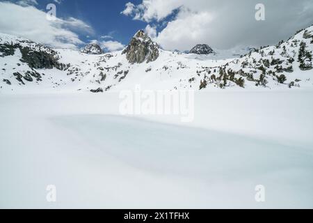 Pacific Crest Trail. Eine schneebedeckte Bergkette mit einem großen Wasserkörper im Vordergrund. Der Himmel ist klar und blau mit ein paar Wolken Stockfoto