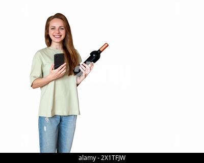 Joyful pretty brunette woman wearing casual t-shirt and jeans holding wine bottle and mobile phone in her hands and smiling. Liquor store consumer. Stockfoto