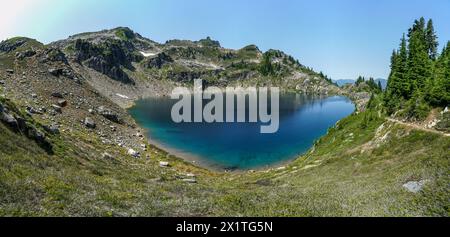 Pacific Crest Trail. Ein großer Wasserkörper, umgeben von Bäumen und Felsen. Der See ist ruhig und friedlich, mit einer klaren blauen Farbe. Die Umgebung Stockfoto