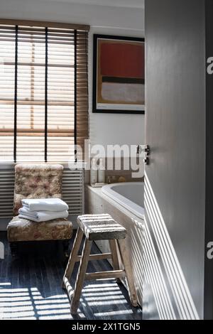 Blick durch die Tür zum Badezimmer mit sonnendurchfluteten venezianischen Jalousien in Chelsea Home, London, Großbritannien Stockfoto