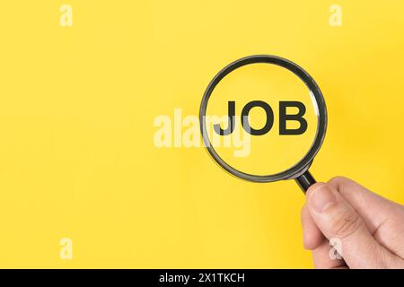 Vergrößerungsglas über einem auf gelbem Hintergrund isolierten Word Job Stockfoto