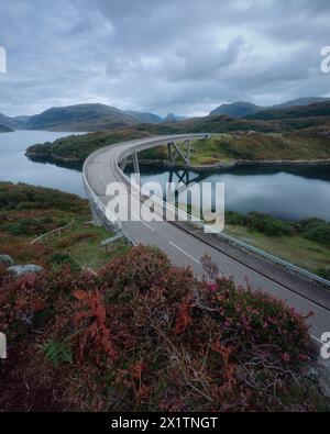 Gekrümmte Brücke, die den See im Herbst überquert. Kylesku Bridge überquert den Loch A Chairn Bhain in Sutherland, an der Nordküste 500, Schottland Stockfoto