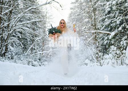 Niedrigwinkelansicht einer lachenden Frau, die im Winterwald Schnee tritt Stockfoto