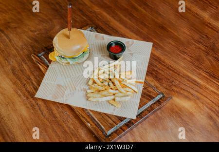 Blick von oben auf den Cheeseburger mit Pommes frites auf Holztisch. Köstlicher Hamburger mit Pommes frites auf einem Holztisch Stockfoto