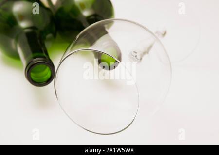 Nahaufnahme von zwei verbrauchten und leeren grünen Glasflaschen Rotwein mit geneigtem Weinglas auf weißem Hintergrund, Studiokomposition, Quebec, Kanada Stockfoto