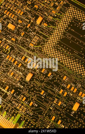 Nahaufnahme einer dunkelgrünen und goldgelb beleuchteten elektronischen Computerplatine mit Linien und silbernen Lötpunkten, Studio-Komposition, Quebec Stockfoto