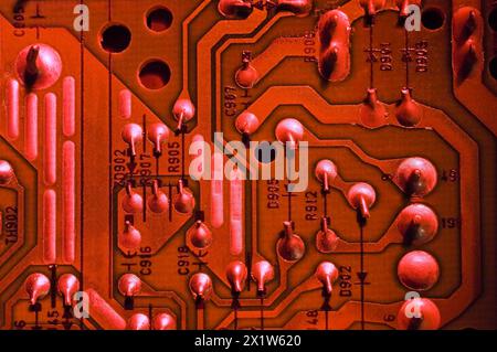 Nahaufnahme einer rot beleuchteten elektronischen Computerplatine mit silbernen Lötpunkten, Zahlen und Linien, Studio Composition, Quebec, Kanada Stockfoto