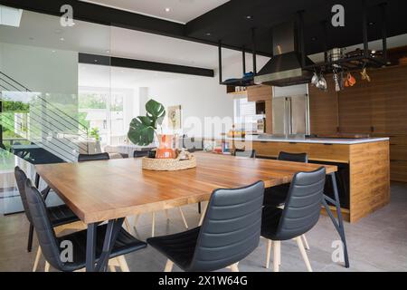 Esstisch aus amerikanischem Walnussholz und schwarze Ledersessel mit Eschenholzbeinen im Esszimmer in einem modernen Wohnhaus im Cube-Stil Stockfoto