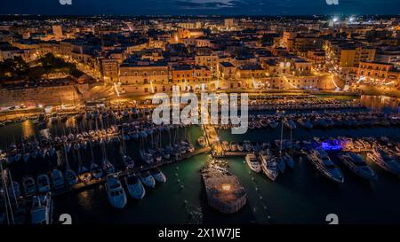 Blick aus der Vogelperspektive auf das Meer und die Altstadt von Bisceglie in Apulien mit Drohne bei Nacht. Stockfoto