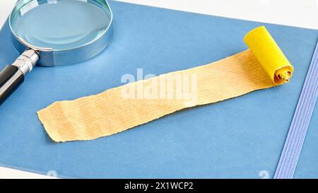 Ein Stück Papier, zerknittertes Papier, ein entfaltetes Blatt Papier auf einem blauen Notizbuch Stockfoto