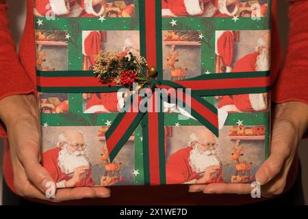 Nahaufnahme der Arme und Hände der Frau, die ein Weihnachtsgeschenk in einer Box halten und anbieten, Studio-Komposition, Quebec, Kanada. Dieses Bild ist ein Modell freigegeben. Stockfoto