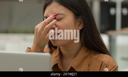 Überarbeitete asiatische Frau Mädchen arbeitet Laptop im Café leiden Augenanstrengung müde chinesische Geschäftsfrau Freelancer überladen mit Computerarbeit reiben Augen Schmerzen Stockfoto