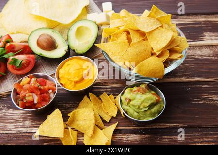 Schüssel mit leckeren mexikanischen Nachos mit Guacamole auf Holztisch Stockfoto