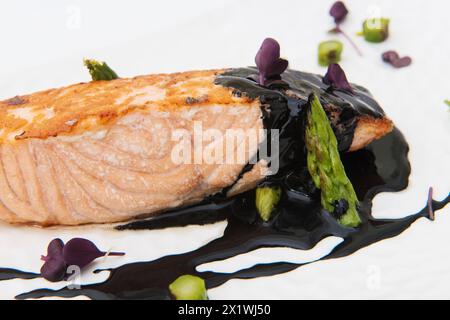 Lachssteak mit Spargel und Balsamico auf weißem Hintergrund Stockfoto