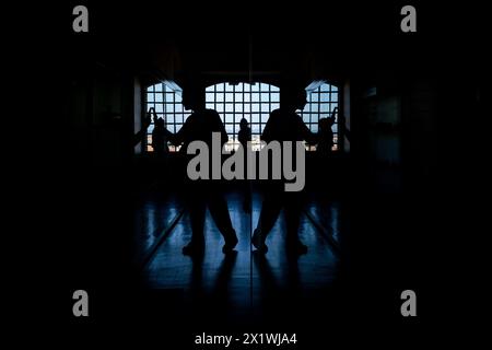 Eine symmetrische Reflexion der Silhouette eines Touristen, der mit seinem Smartphone im Centro Portugues de Fotografia in Porto im Norden fotografiert Stockfoto