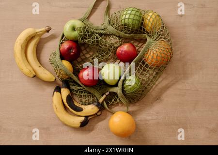 Blick von oben auf die Einkaufstasche mit verschiedenen Früchten, darunter verwöhnte und frische Bananen, reife grüne und rote Äpfel und saftige Orangen Stockfoto