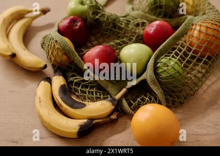 Teil der Einkaufstasche mit verschiedenen Früchten auf dem Tisch, darunter verwöhnte und frische Bananen, reife Orangen, rote und grüne Äpfel Stockfoto