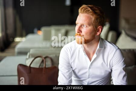 Porträt eines erfolgreichen Geschäftsmannes auf Geschäftsreise, der im Hotelzimmer sitzt Stockfoto