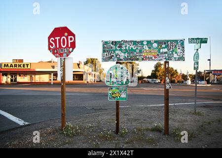 BAKER, KALIFORNIEN - 14. APR 2024: Schilder an der Ausfahrt der I-15 in Baker mit Aufklebern bedeckt. Stockfoto
