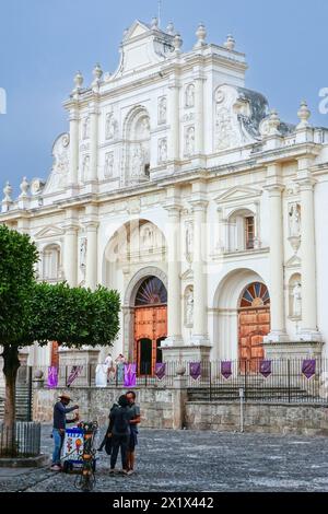 Ein Paar kauft Eis von einem Verkäufer auf dem Parque Central mit der 15. San José Kathedrale Antigua in Antigua, Guatemala. Die einst prächtige Kathedrale von Antigua Guatemala wurde 1717, 1773, 1874, 1918 und 1976 durch Erdbeben zerstört. Stockfoto