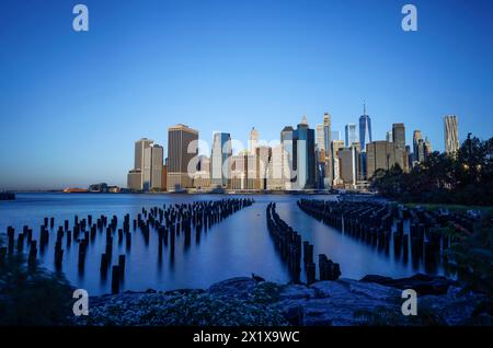 Wolkenkratzer im Finanzviertel Lower Manhattan, die am frühen Morgen New York über den East River vom Old Pier 1 im Brooklyn Bridge Park Greenway aus gesehen werden Stockfoto