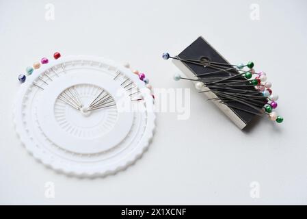Mehrfarbige Pins auf weißem Hintergrund. Stifte und ein Nähmagnet. Stockfoto