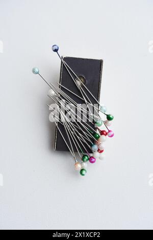 Mehrfarbige Pins auf weißem Hintergrund. Stifte und ein Nähmagnet. Stockfoto
