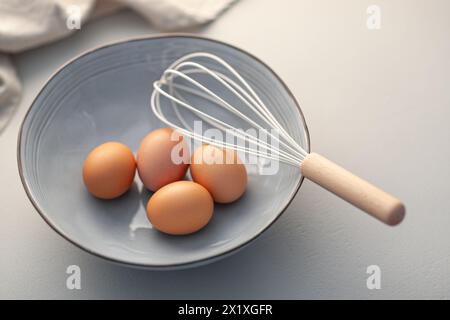 Zubereitung zum Backen mit Eiern und Schneebesen in einer Keramikschale auf einer Küchentheke Stockfoto