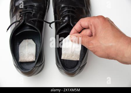Nahaufnahme der Hand legt den Teebeutel in Schuhe. Konzept der Entfernung unangenehmer Gerüche Stockfoto