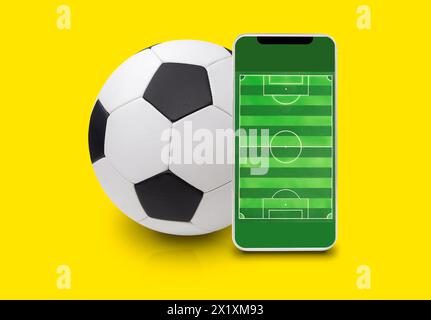 Handy-Fußball online mit gelbem Hintergrund Stockfoto