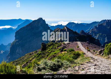 Beschreibung: Weibliche Touristen spazieren entlang des Panorama-Bergwegs und genießen die malerische Aussicht an einem sonnigen Sommertag. Pico do Arieiro, Madeira Islan Stockfoto