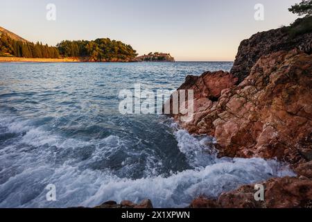 Weitwinkelblick auf das Meer mit rauschenden Wellen auf Felsen im Sonnenuntergang Stockfoto