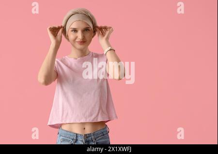Lächelnde junge Frau nach Chemotherapie auf rosa Hintergrund. Magenkrebskonzept Stockfoto