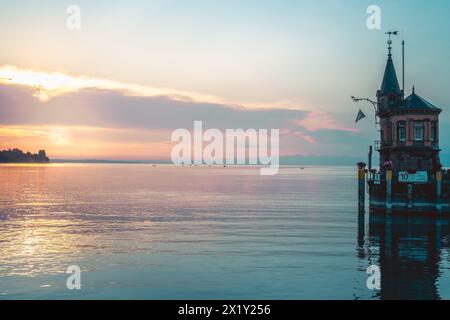 Beschreibung: Schöner Blick auf Sonnenaufgang von der Imperia-Statue zum Leuchtturm am Hafeneingang und am Bodensee in den frühen Morgenstunden. Steamer Harbour, Co Stockfoto