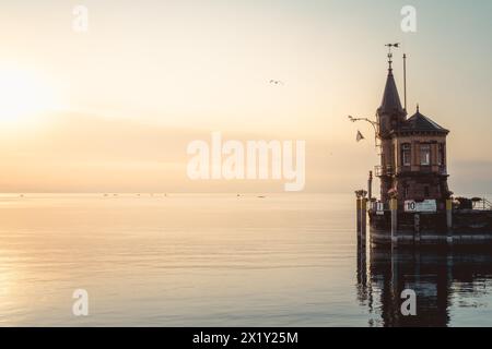 Beschreibung: Schöner Blick auf Sonnenaufgang von der Imperia-Statue zum Leuchtturm am Hafeneingang und am Bodensee in den frühen Morgenstunden. Steamer Harbour, Co Stockfoto