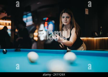 Junge Frau, die mit Freunden am Abend in einer Bar Billard spielt Stockfoto